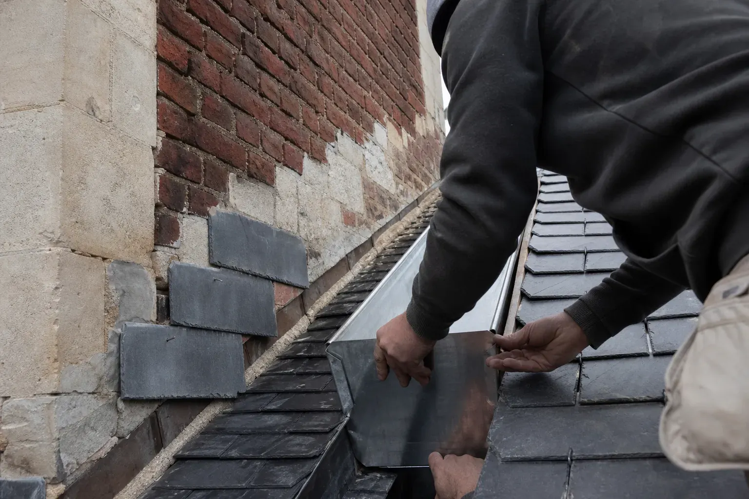 Tronçon de chéneau en zinc neuf descendu à sa place entre deux versants de toiture